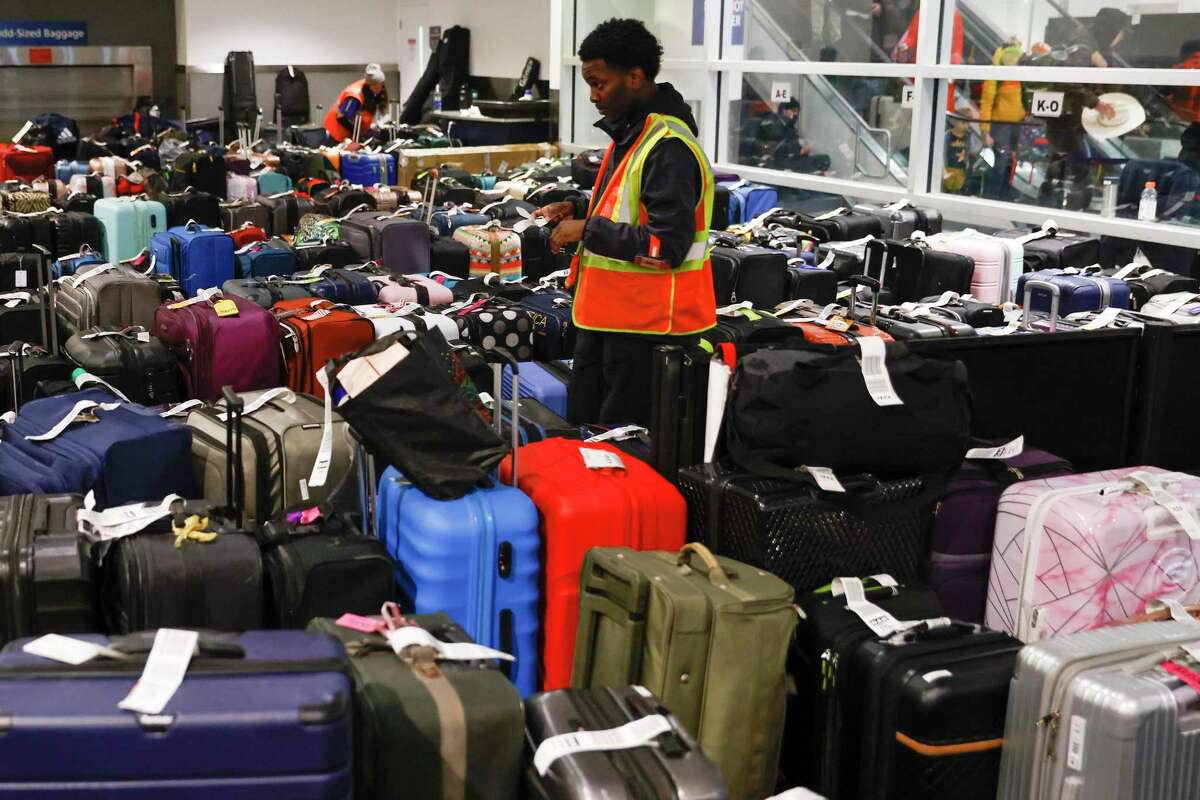 机场工作人员正在整理数百件抵达奥克兰国际机场的行李，而它们的主人却被困在其他地方，因为西南航空公司在奥克兰的几乎所有航班都被取消了。
