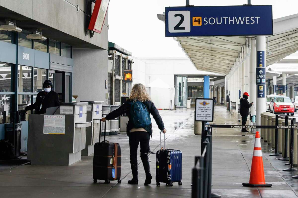 2022年12月27日星期二，在奥克兰国际机场，西南航空几乎所有航班都取消后，一名乘客将行李推到西南航空售票处。
