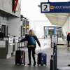 2022年12月27日星期二，在奥克兰国际机场，几乎所有西南航空公司的航班都被取消后，一名乘客将行李推到西南航空公司的售票柜台。