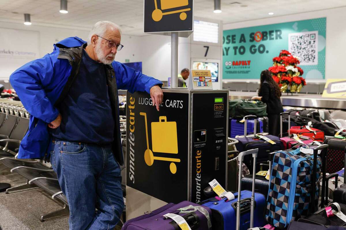 2022年12月27日，周二，伯克利的Gerry MacClelland在他女儿试图飞回奥克兰国际机场时被困，他等待着女儿的行李状况。