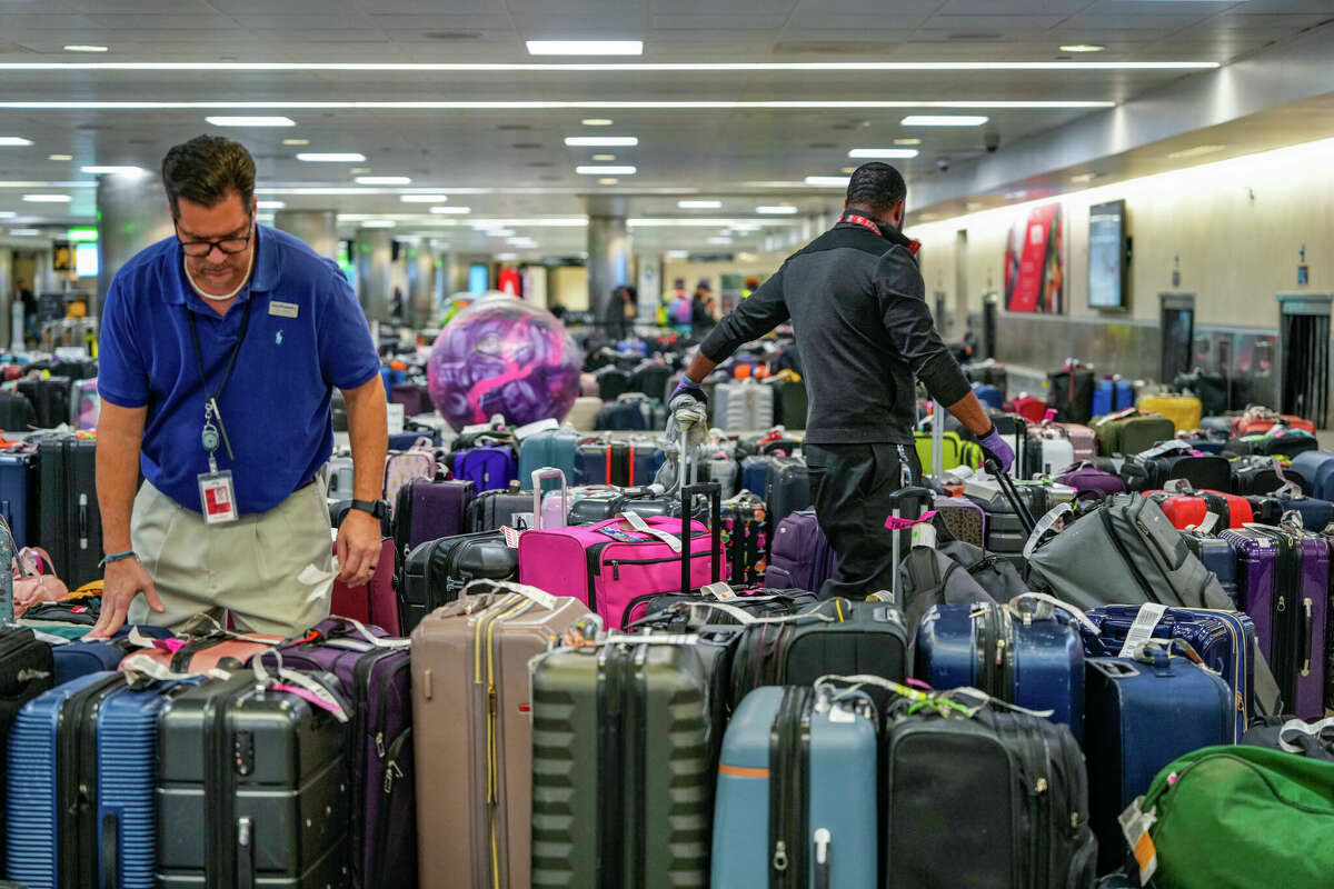 Airport employee, Tom Wilson, searches through hundreds of unclaimed bags as they continue to accumulate in the William P. Hobby Airport baggage claim due to canceled flights on Tuesday, Dec. 27, 2022 at in Houston.