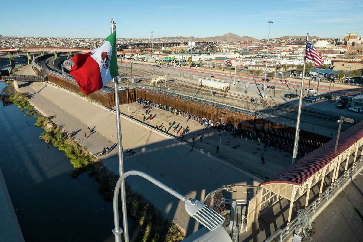 An aerial view of the Mexican and American flags fly over an international bridge as immigrants line up next to the U.S.-Mexico border fence to seek asylum on December 22, 2022 in El Paso, Texas. 