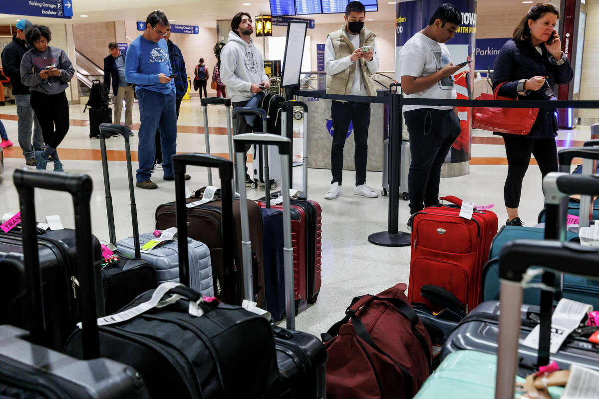 A long line of people wait to reach the Southwest Airlines baggage claim window to find out information about their bags as rows of unclaimed luggage sits around them at the San Antonio International Airport in San Antonio, Texas, Tuesday afternoon, Dec. 27, 2022.