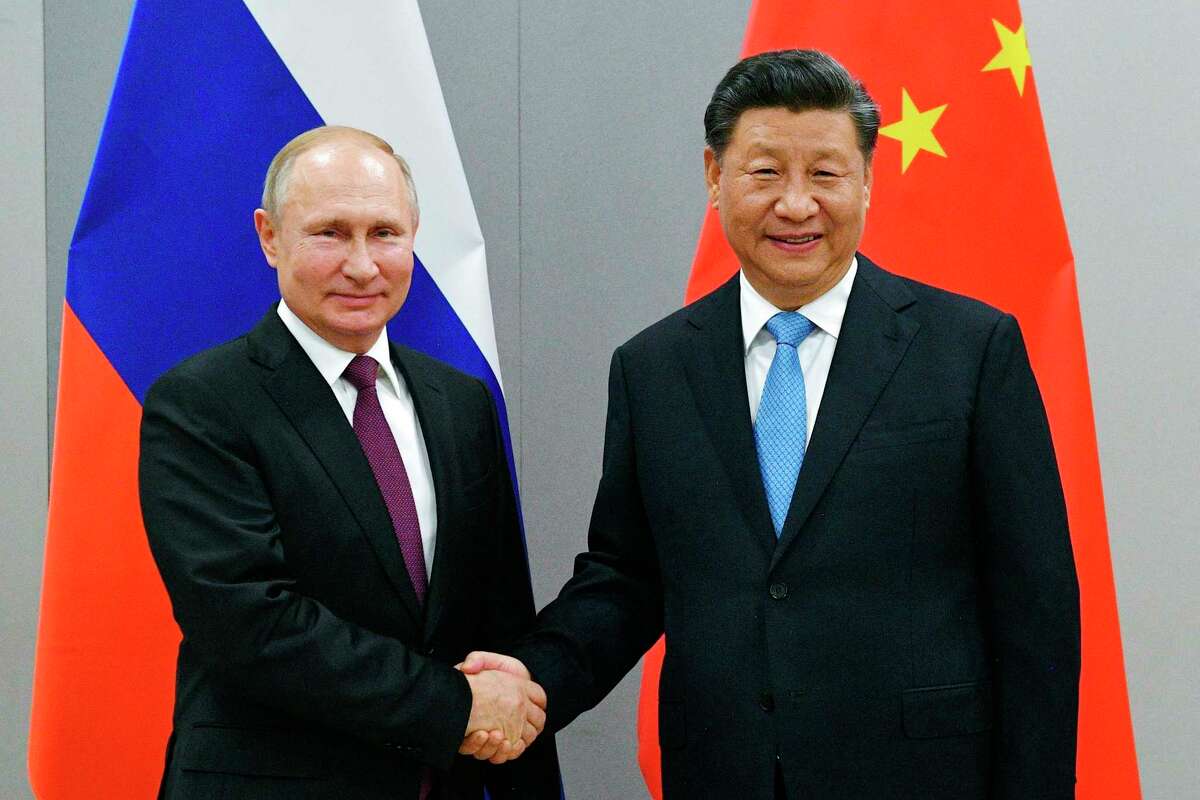 Russian President Vladimir Putin, left, and China's President Xi Jinping shake hands in Brazil in 2019. Xi views Taiwan much the same way as Putin views Ukraine — it rightfully belongs to China.