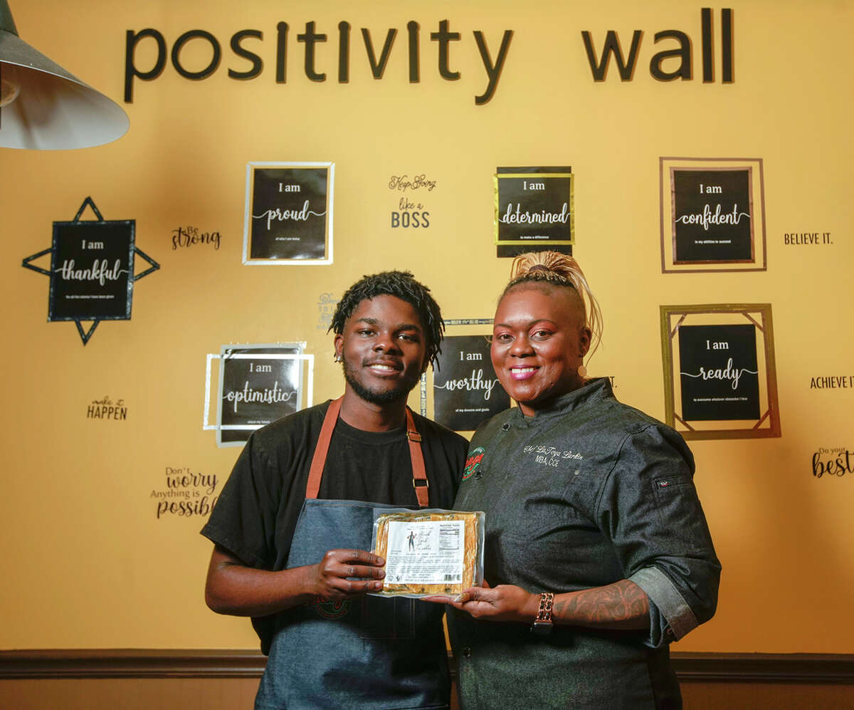 LaToya Larkin, chef and owner of Black Girl Tamales with her son, Xaviar Whatley, hold a package of her collard greens smoked turkey tamales at her deli Mango Deli and Cafe in Houston.