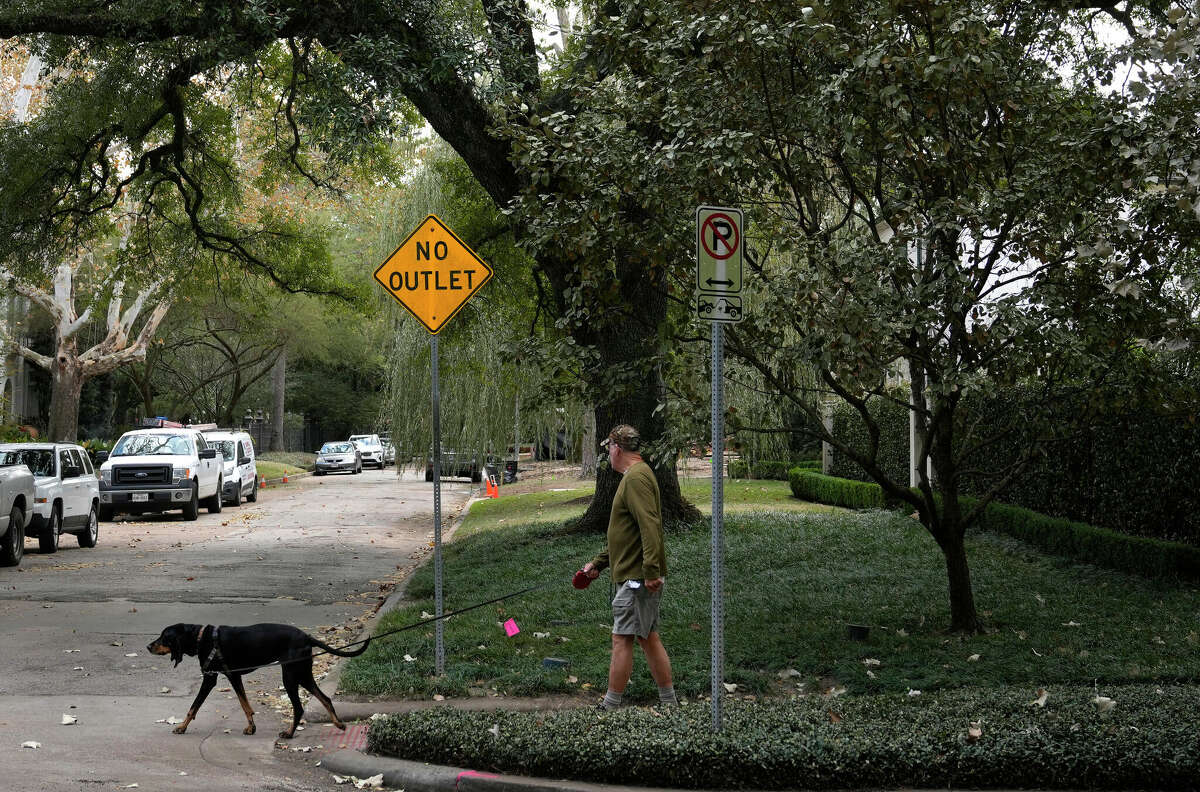 A man walking a dog crosses Waverly Court at Bissonnet in Houston's Museum District on Wednesday, Dec. 28, 2022. Dozens of antisemitic flyers were found in the neighborhood the week before.