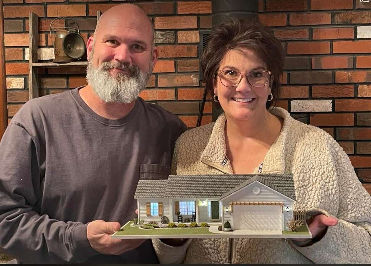 Alton resident Pat Parker's son Jeff Kuechenmeister, and his wife, Jennifer Kuechenmeister, hold the teeny tiny house that she built for them. The replica is of their house in which they lived in O’Fallon, Missouri, before they moved to Sullivan, Missouri. Parker built everything, including the landscaping, except for the wagon wheel, rocking chairs and shingles.