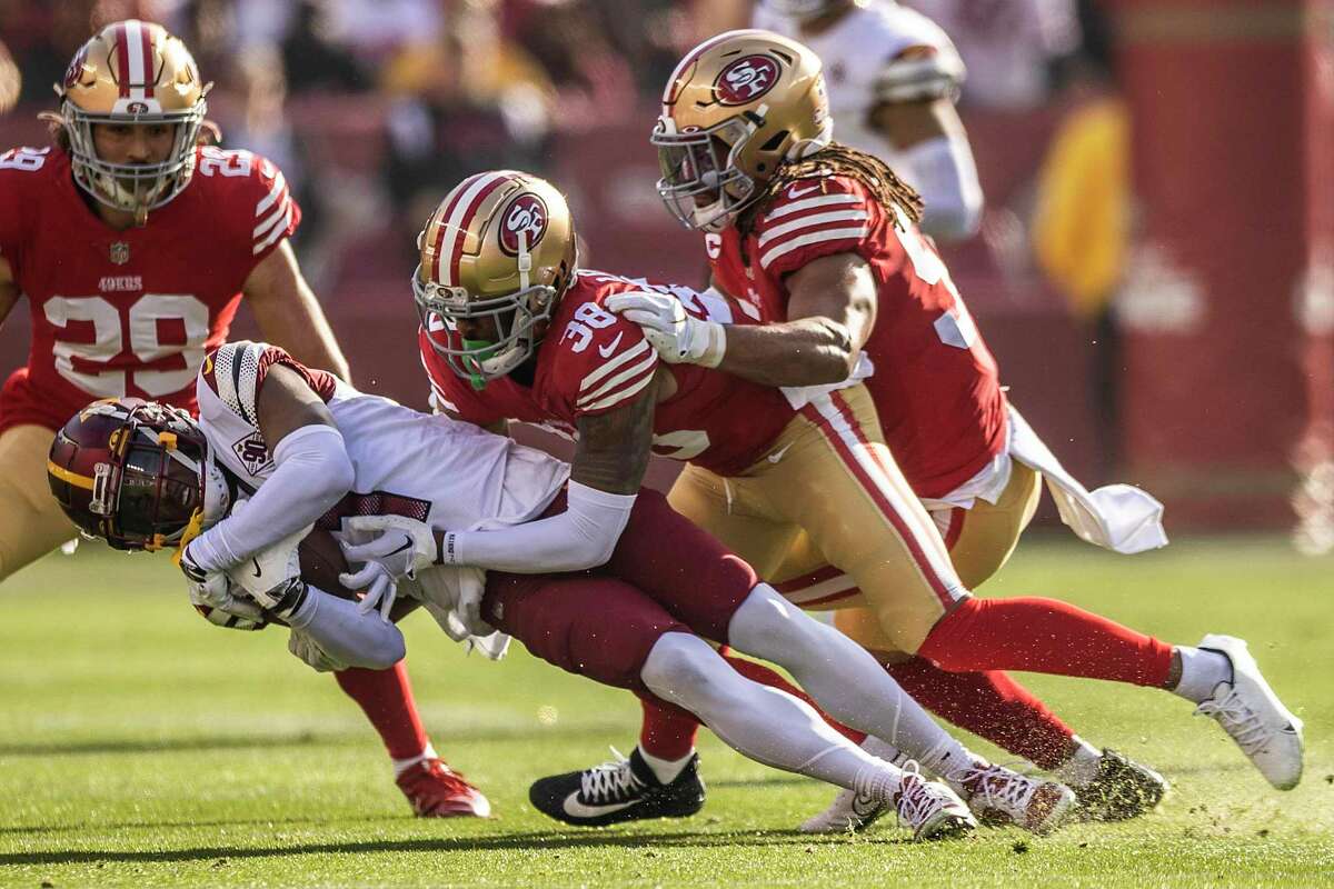 Washington Commanders wide receiver Jahan Dotson (1) is being tackled by San Francisco 49ers cornerback Deommodore Lenoir (38) and linebacker Fred Warner (54) during the first quarter of their NFL football game in Santa Clara, Calif., Saturday, Dec. 24, 2022.
