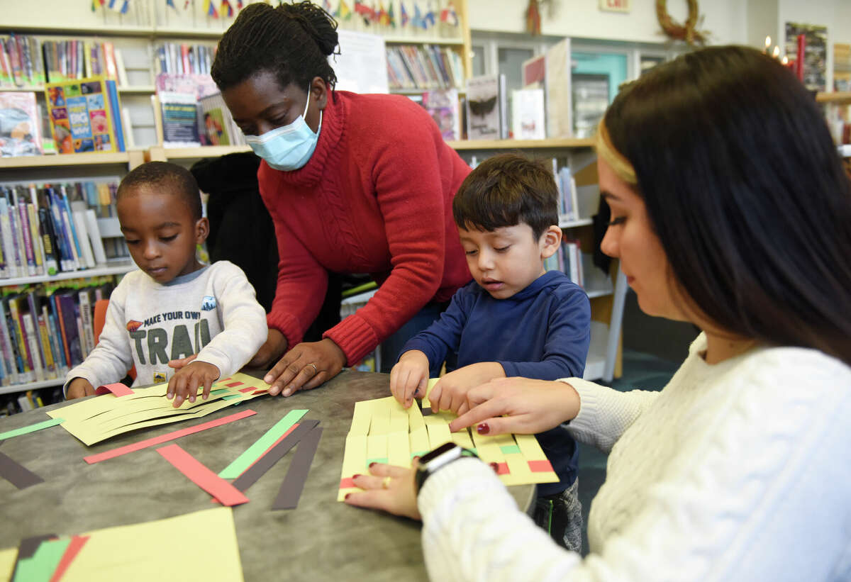 From left, Samuel Fisher, 4, Samantha Fisher, Justin Perez, 4, and South End Branch clerk Vanessa Velez do a paper weaving activity during the Kwanzaa Community Gathering and Celebrations event at Ferguson Library's South End Branch in Stamford, Conn. Thursday, Dec. 29, 2022. Folks celebrated day four of Kwanzaa on Thursday by learning the principle of Ujamaa, meaning cooperative support, through a paper weaving activity. Another event is planned at the South End Branch on Saturday to teach the principle of Kuumba, meaning creativity, with a coloring activity.
