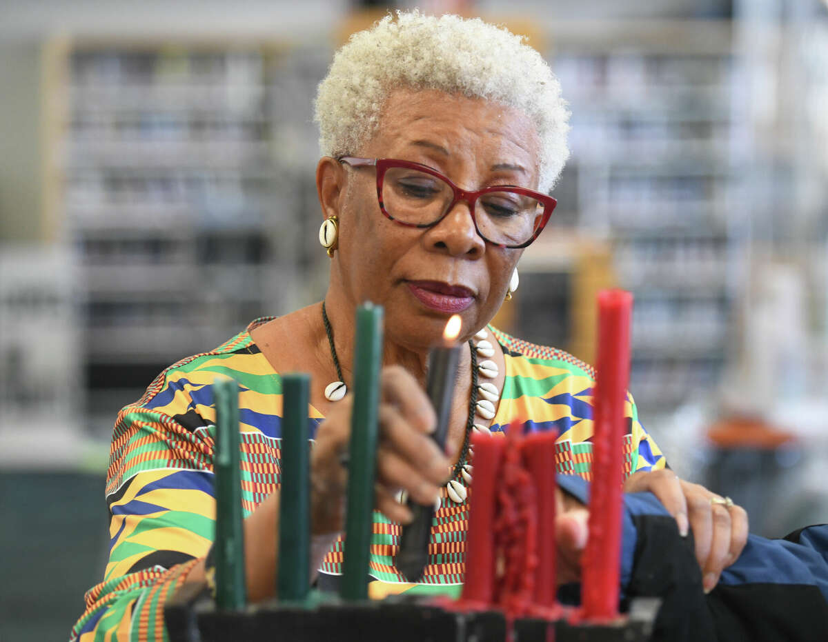 South End Branch supervisor Josephine Fulcher-Anderson lights four candles during the Kwanzaa Community Gathering and Celebrations event at Ferguson Library's South End Branch in Stamford, Conn. Thursday, Dec. 29, 2022. Folks celebrated day four of Kwanzaa on Thursday by learning the principle of Ujamaa, meaning cooperative support, through a paper weaving activity. Another event is planned at the South End Branch on Saturday to teach the principle of Kuumba, meaning creativity, with a coloring activity.