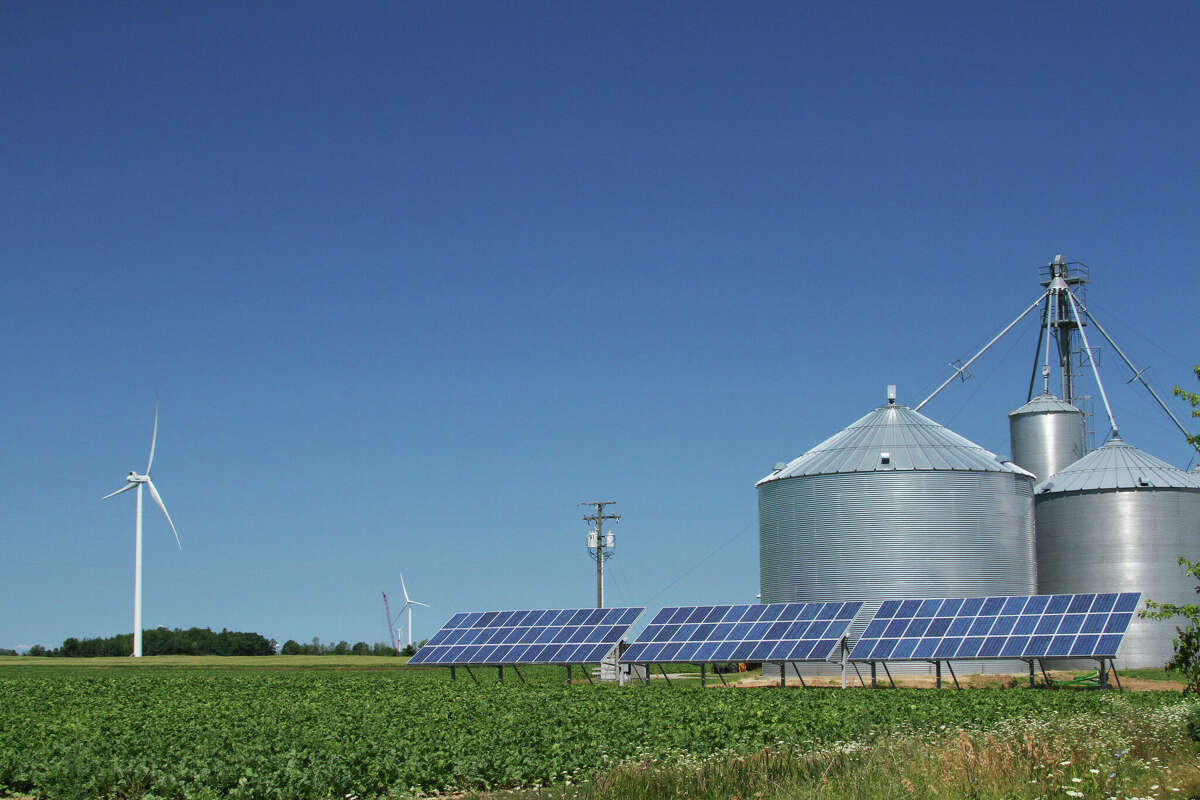 Windmill and solar panels near farm grain bins in Palms, Michigan. Michigan recently received a total of $1,687,490 in grants through the Rural Energy for America Program.