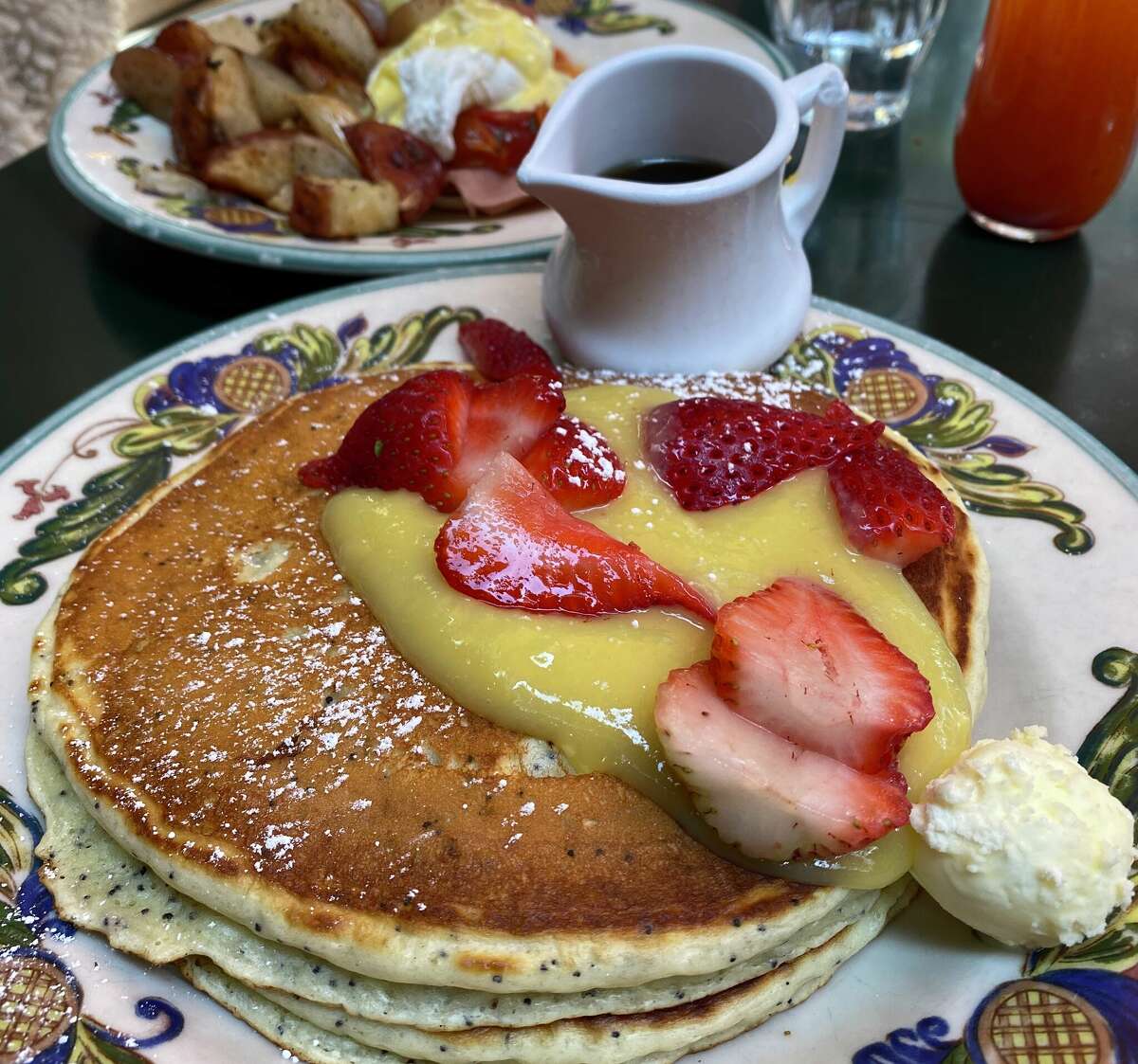 A stack of pancakes with strawberries, butter and side of syrup at Zazie. 