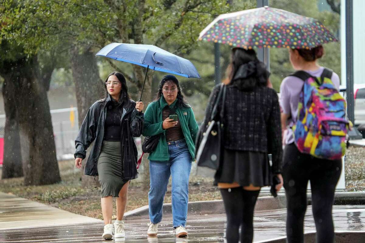 Pedestrians shelter under umbrellas as they protect themselves from the rain in the Museum District on Thursday, Dec. 29, 2022 in Houston.