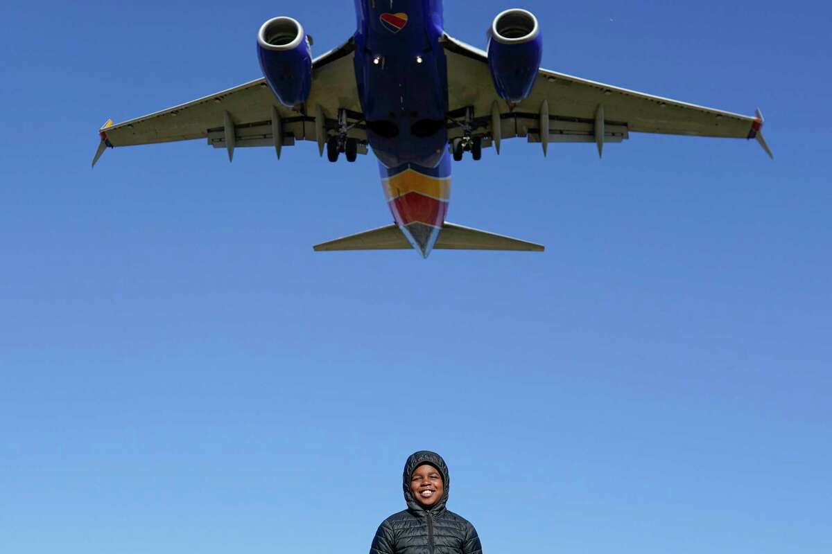 Orin Okubadejo, 12, of Maryland, poses for a photo for his family as a Southwest Airlines plane flies low over Gravelly Point on approach to Ronald Reagan Washington National Airport on Friday. The airline returned to a relatively normal flight schedule Friday, as the focus shifts to making things right with what could be well more than a million passengers who missed family connections or flights home during the holidays, and many of whom are still missing luggage.