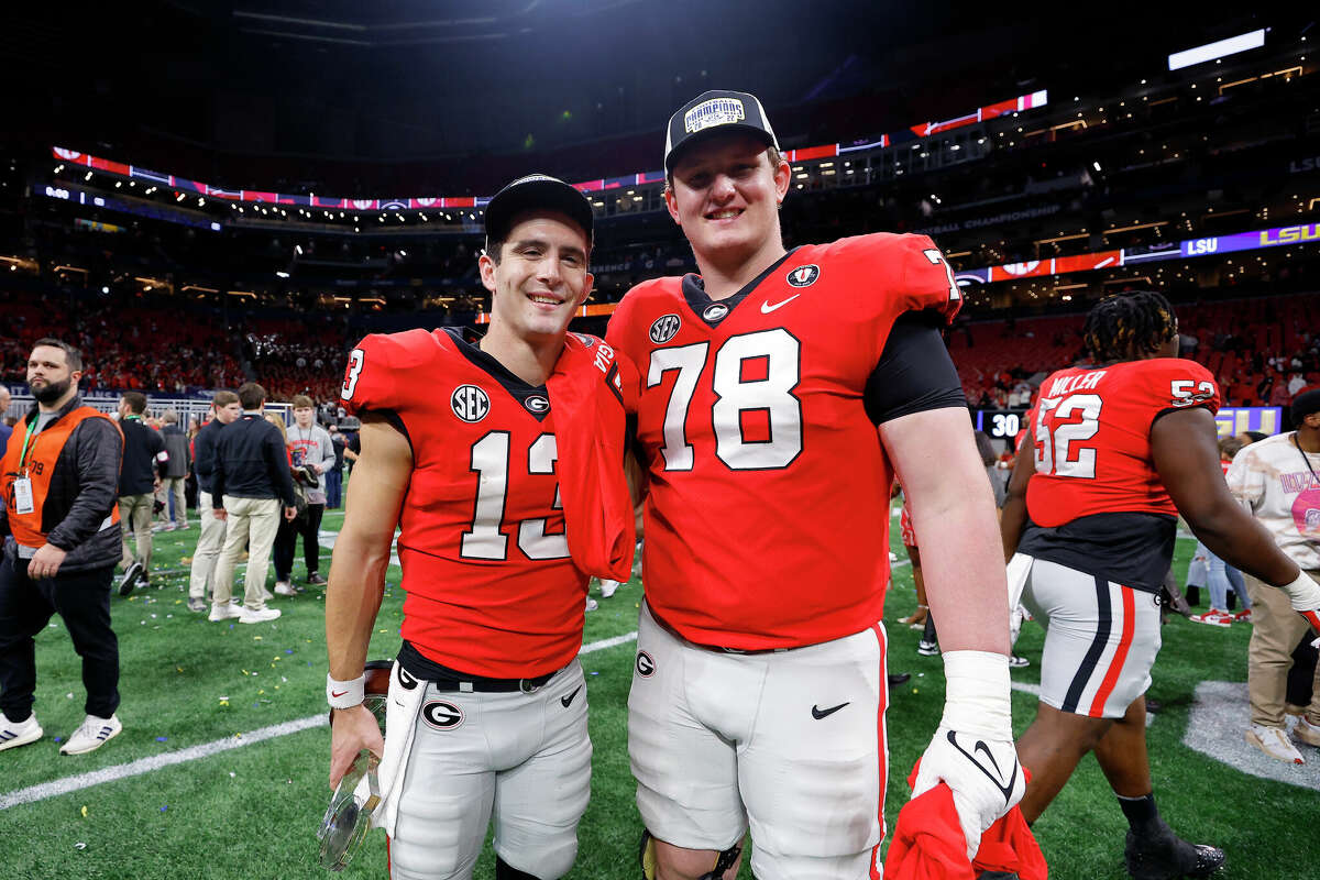 Stetson Bennett #13 and Chad Lindberg #78 of the Georgia Bulldogs celebrate after defeating the LSU Tigers in the SEC Championship match on December 3, 2022, at the Mercedes-Benz Stadium in Atlanta, Georgia.