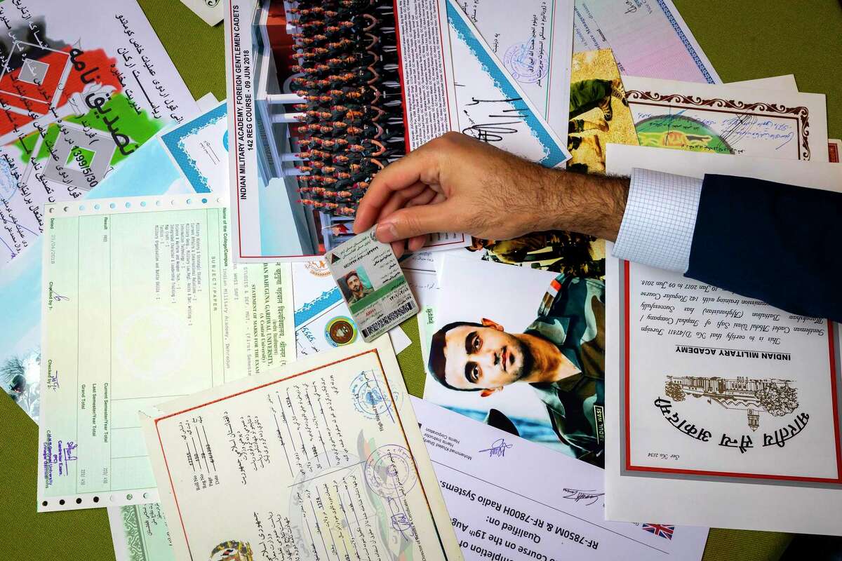 Sami-ullah Safi sorts through dozens of certificates and photos to pick up his brother’s ID card.