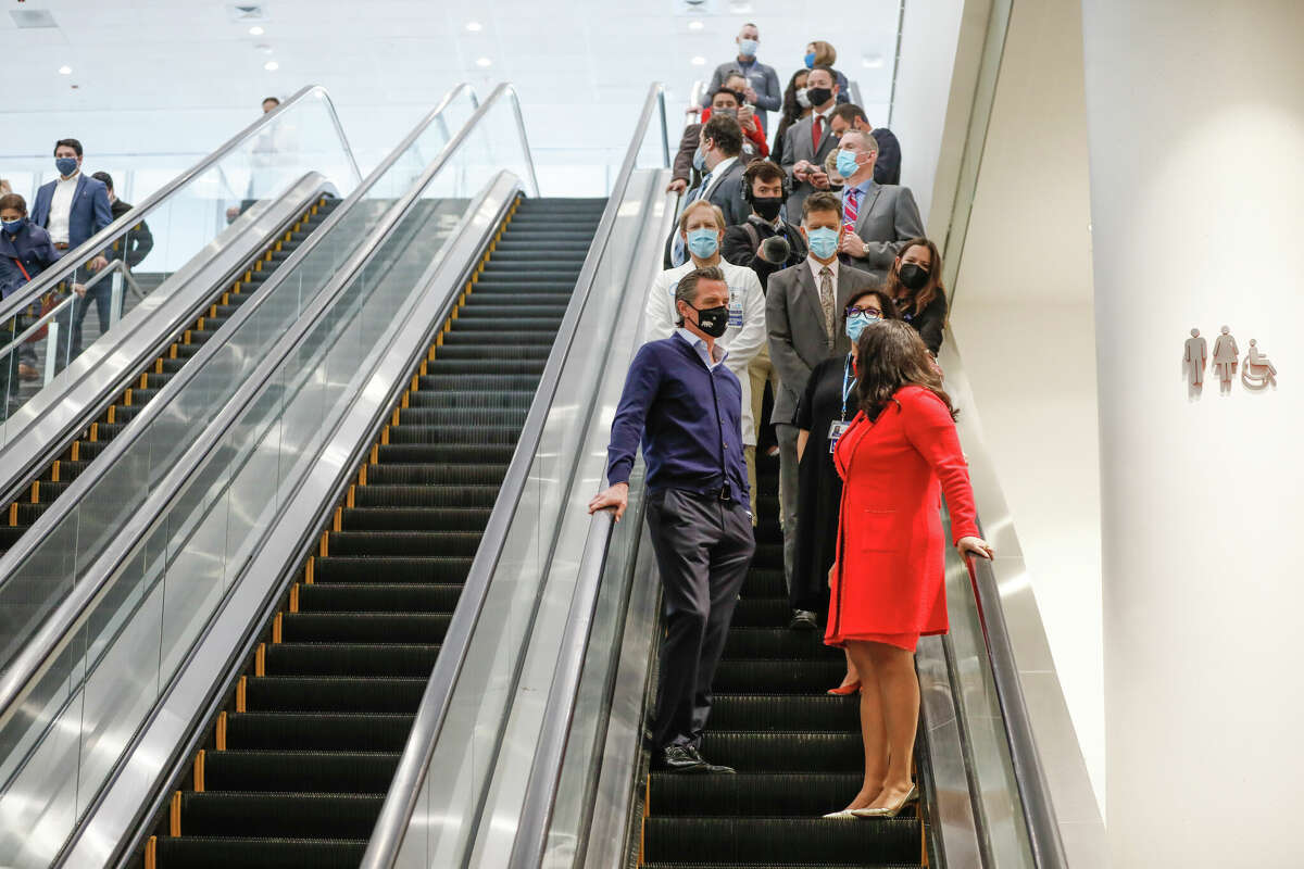 Gov. Gavin Newsom, center, and Mayor London Breed, right, ride the escalator inside the Moscone Center in February 2021.