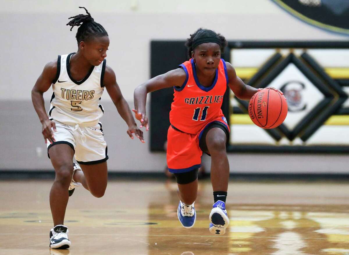 Grand Oaks' Bree Riley (11) drives past Conroe's Ladonna Brown (5) during the second quarter of a District 13-6A high school basketball game at Conroe High School, Friday, Dec. 30, 2022, in Conroe.