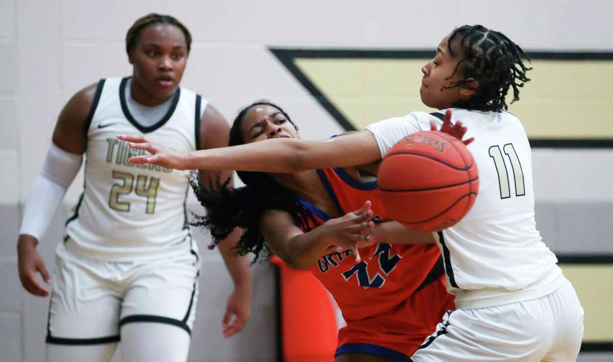 Conroe's Luisa Hamann (22) gets hit in the face as she passes to Conroe's Genesis Hudspeth (11) during the second quarter of a District 13-6A high school basketball game at Conroe High School, Friday, Dec. 30, 2022, in Conroe.