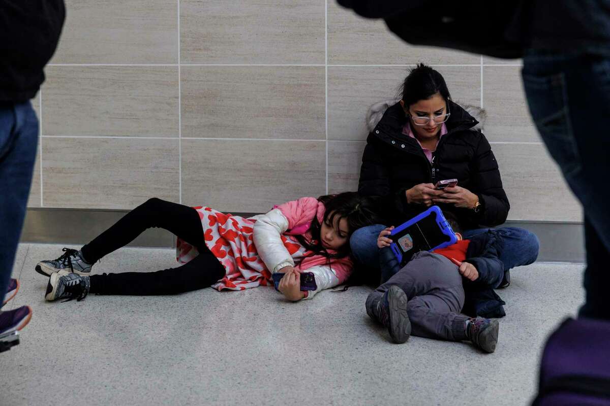 Cristi de Tkachenko, 43, and her children Alejandra, 8, and Ivan, 3, wait for her husband to reach the Southwest Airlines ticket counter to deal with their canceled flights on Dec. 27, 2022. The family from Monterrey, Mexico, decided to take flight vouchers.