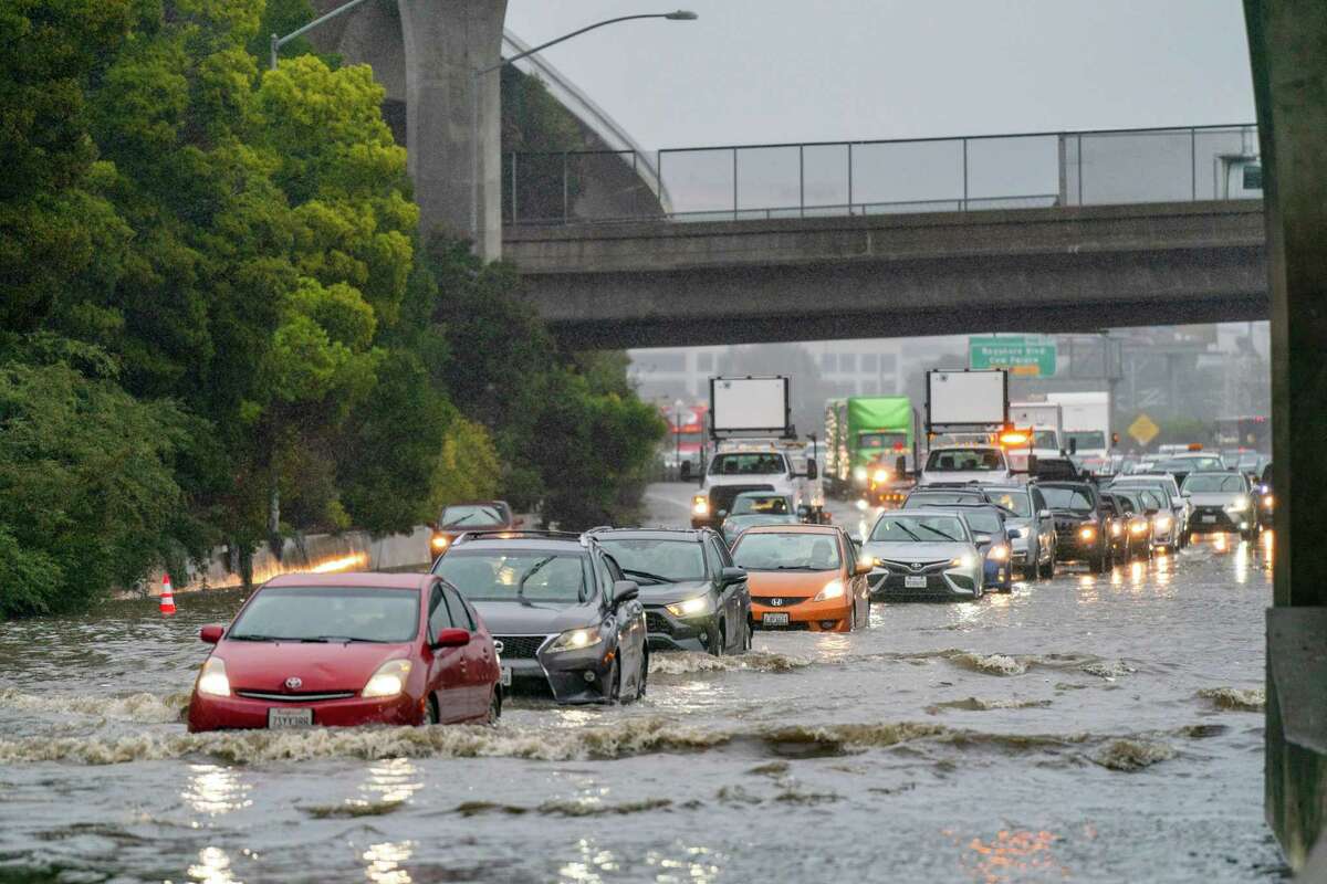 Cars attempt to drive through flooding waters as high as three feet along the Northbound 101 in South San Francisco on Saturday, Dec. 31, 2022.