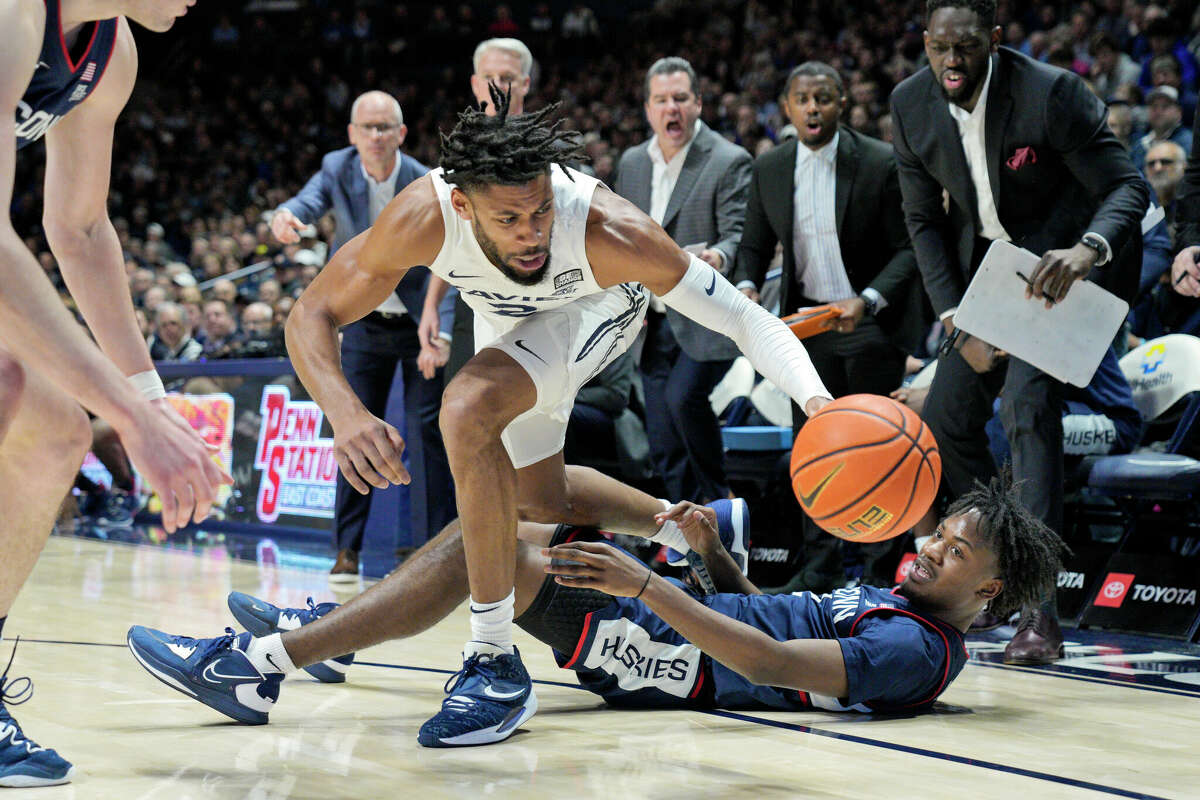 Xavier forward Jerome Hunter (2) fights for a loose ball against Connecticut's Tristen Newton, right, during the first half of an NCAA college basketball game, Saturday, Dec. 31, 2022, in Cincinnati. (AP Photo/Jeff Dean)