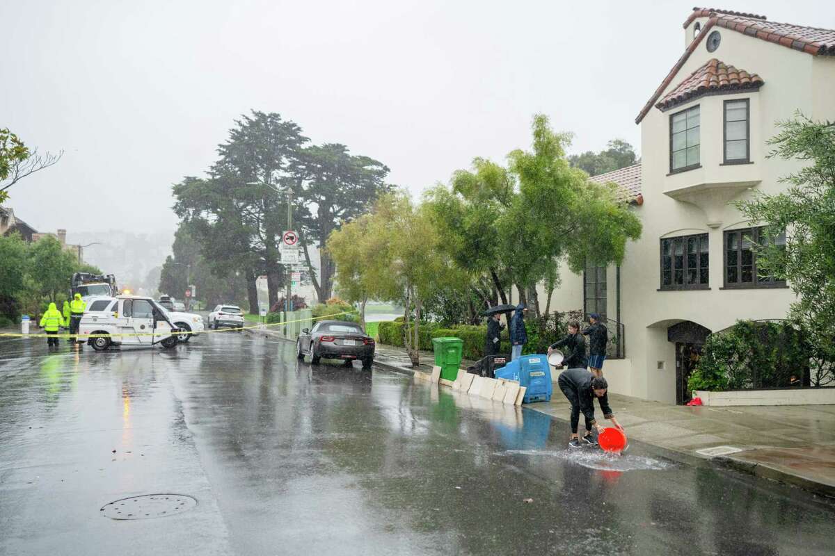 A household  uses buckets to region   h2o  that has flooded their store  on  Baker Street successful  Marina successful  San Francisco connected  Saturday, Dec. 31, 2022.