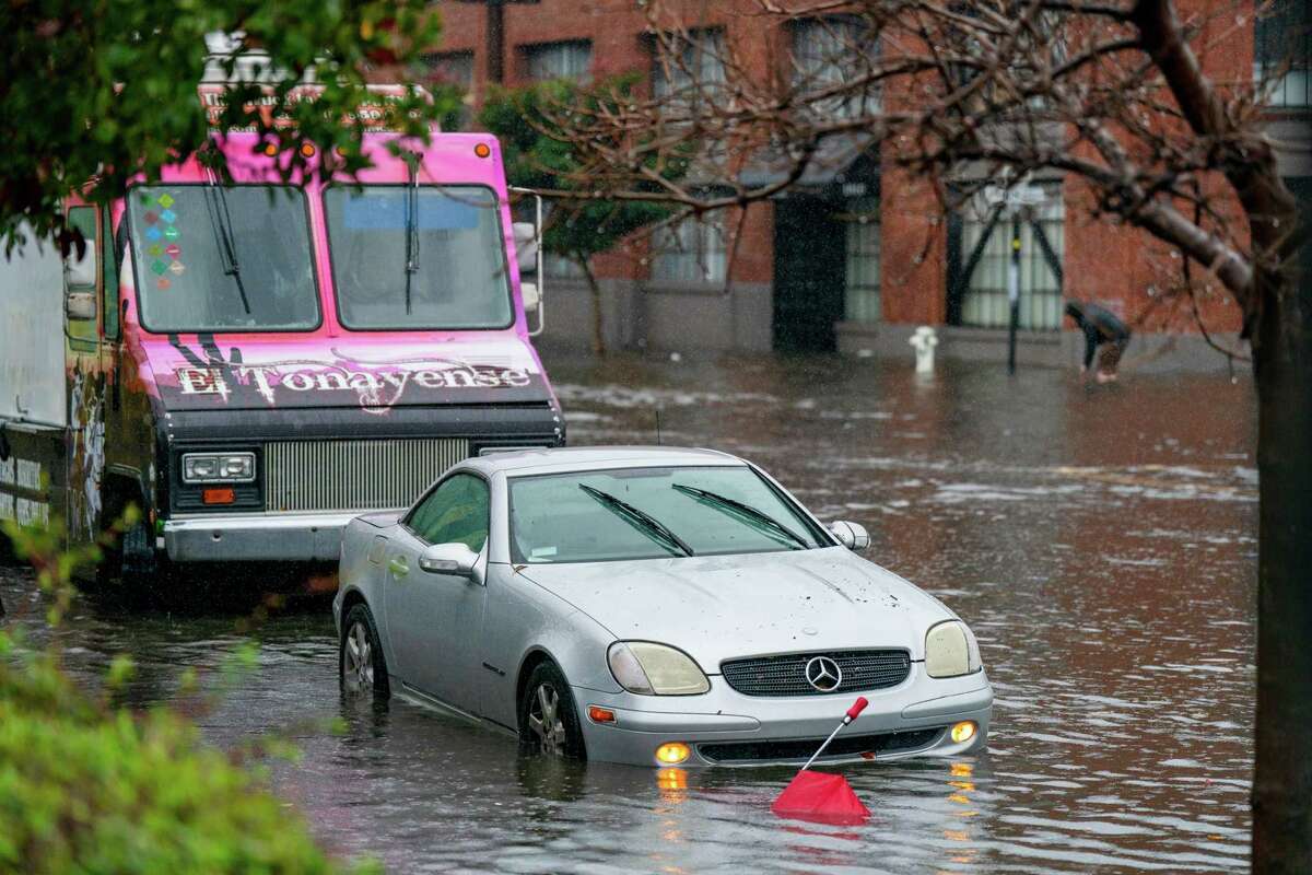 Cars sit in flooded water on 14th Street in the Mission District of San Francisco.