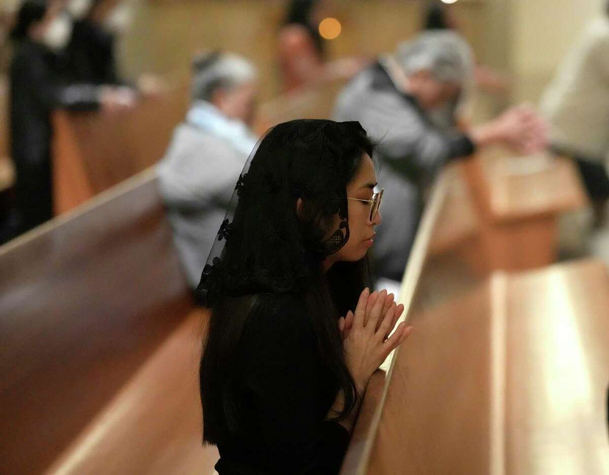 A woman prays as Auxiliary Bishop Italo Dell’Oro conducts mass, which also honored Pope Benedict XVI at the Co-Cathedral of the Sacred Heart on Saturday, Dec. 31, 2022 in Houston.