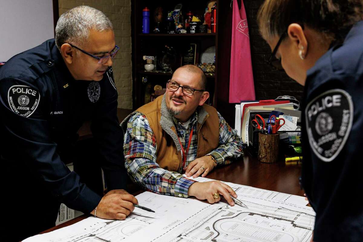 Judson ISD’s new director of safety and security, Jesus Hernandez, center, talks with Lt. Frank Garcia, left, over a map of D. W. Rutledge Stadium in the district police department office of Chief Teresa Ramon, right, in Converse on Dec. 16. The district created Hernandez’s position this year in response to the tragedy in Uvalde.