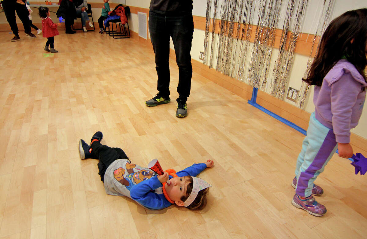 Sammy Shifflez lays on the floor with him and other children and whistles paper horns as they ring in the New Year at the Marx Family Black Box Theater at Greenwich Library in Greenwich, Connecticut, at a dance party and other fun activities (3 years old).  December 31, 2022.