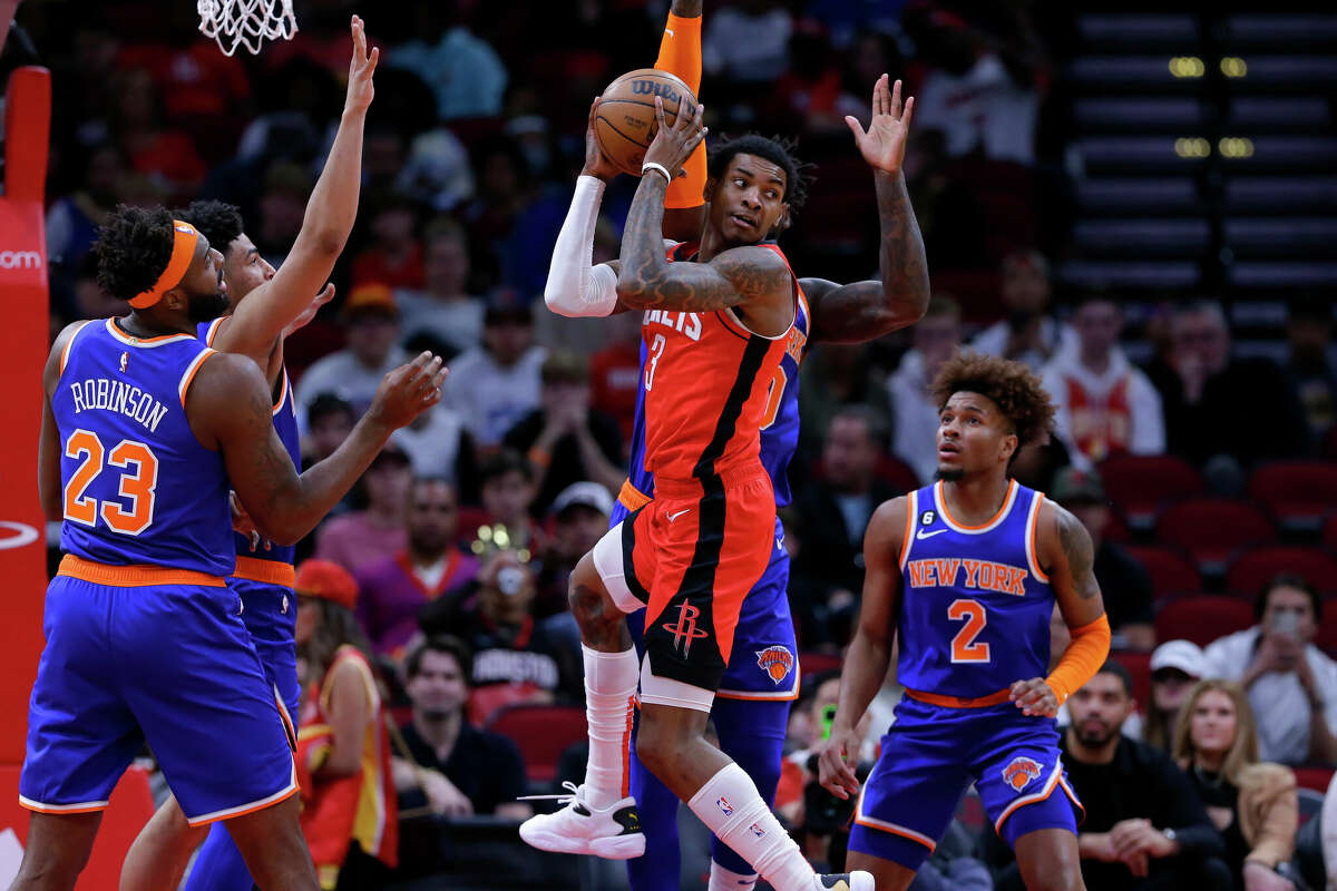 Houston Rockets guard Kevin Porter Jr., front center, pulls down a rebound in the middle of New York Knicks players, from left to right, New York Mitchell Robinson (23), Quentin Grimes, Julius Randle and Miles McBride (2) during the first half of an NBA basketball game Saturday, Dec. 31, 2022, in Houston. (AP Photo/Michael Wyke)