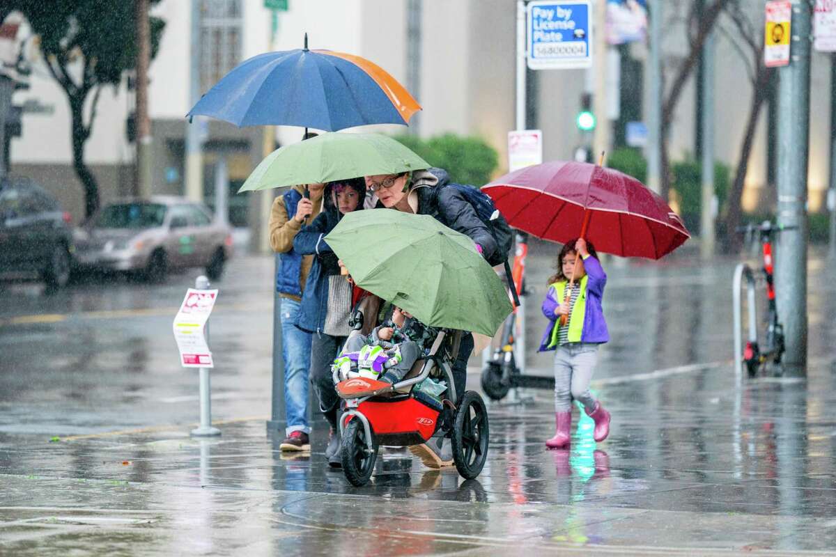 A family prepares for rain walks along the Embarcadero on Saturday, December 31, 2022, in San Francisco, California.
