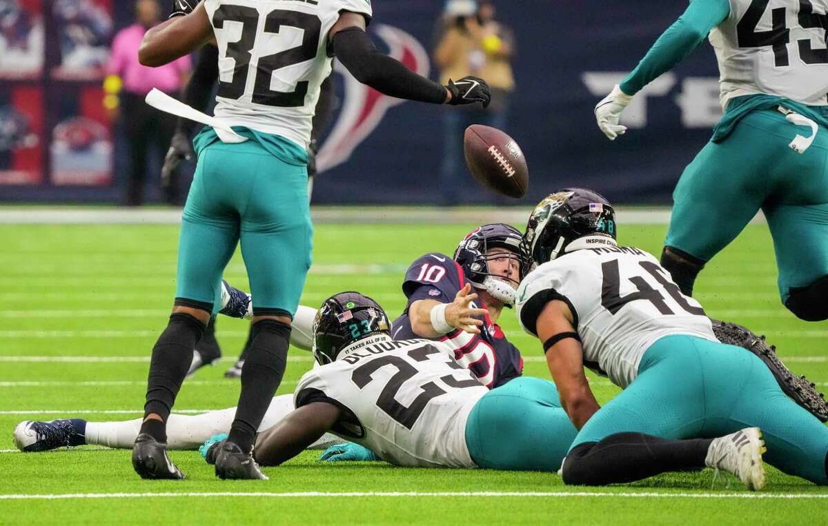 Houston Texans quarterback Davis Mills (10) loses control of the ball as he was brought down by Jacksonville Jaguars linebacker Foyesade Oluokun (23) on the keeper during the second quarter of an NFL football game at NRG Stadium on Sunday, Jan. 1, 2023, in Houston.