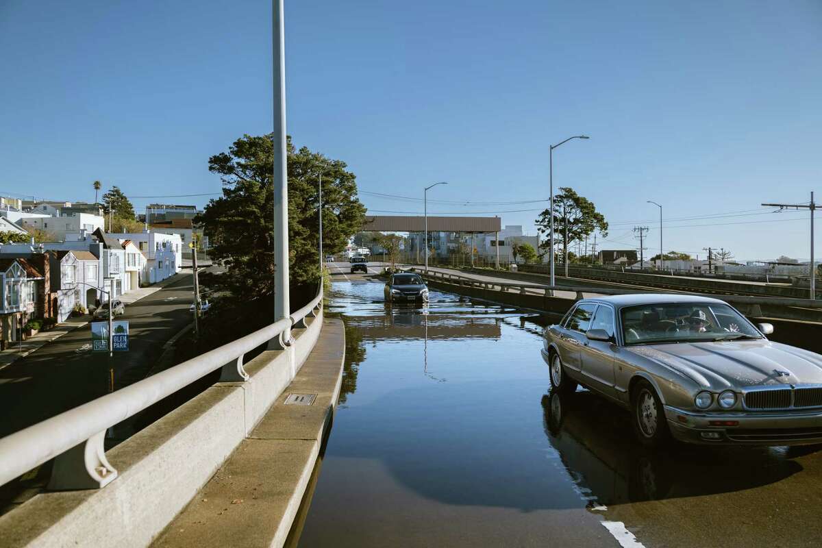 Maria Haro waits in her car in a tow truck after trying to cross the flooded Monterey exit of Highway 280 towards the Glenn Park District in San Francisco, California, on Sunday, January 1, 2022.