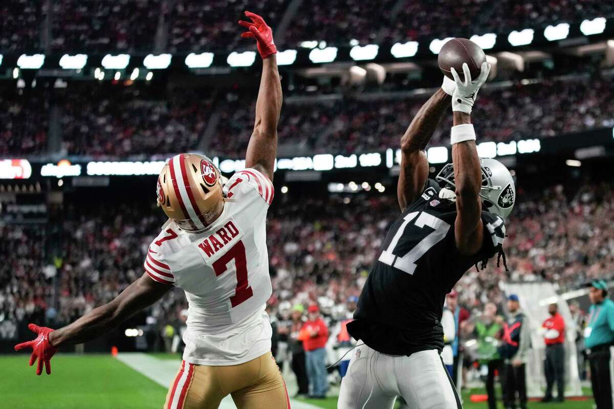 Las Vegas Raiders wide receiver Davante Adams (17) catches a four-yard touchdown pass while being defended by San Francisco 49ers cornerback Charvarius Ward during the first half of an NFL football game between the San Francisco 49ers and Las Vegas Raiders, Sunday, Jan. 1, 2023, in Las Vegas. (AP Photo/John Locher)