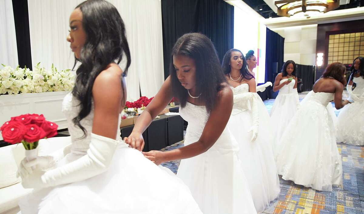 Debutante Nya Livingston fixes the buttons on fellow debutante Reagan Peppers dress before their individual photos participate in the Houston Chapter's 32nd annual Jack & Jill Debutante Ball at Hilton Americas Houston on Thursday, Dec. 29, 2022 in Houston.