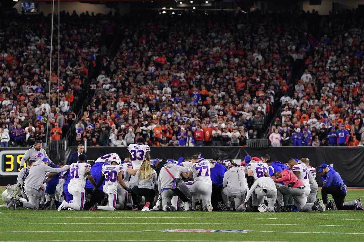 Buffalo Bills players huddle and pray after teammate Damar Hamlin collapsed on the field after making a tackle against the Bengals during the first quarter in Cincinnati on Monday night.