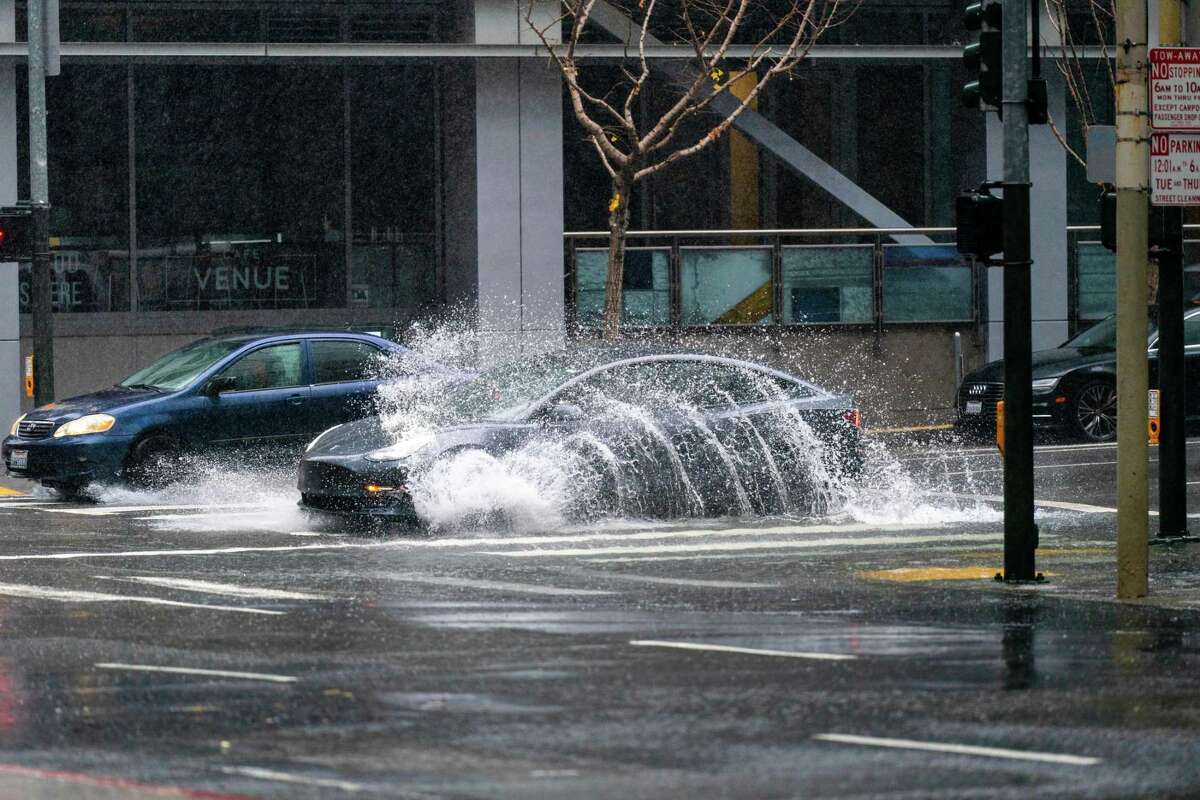 A car splashes through a large puddle that partially fills the intersection at Howard and Fremont streets in San Francisco on Saturday.