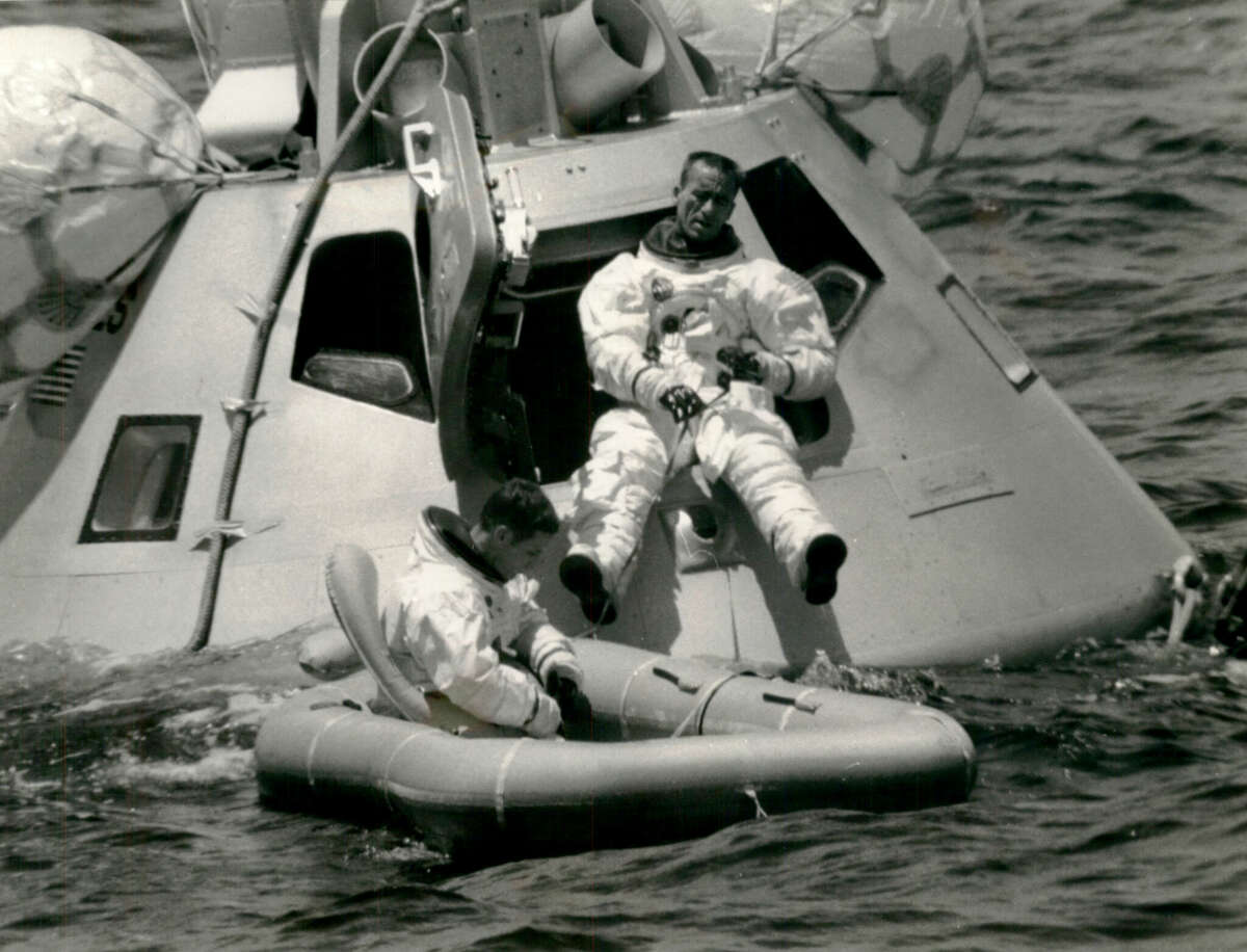 Cape Kennedy, FL: Civilian astronaut Walter Cunningham comes out of the floating Apollo 7 capsule during evacuation training at Cape Kennedy, Fla., while, in the liferaft, Air Force Major Donn F. Eisele works at safety procedures.