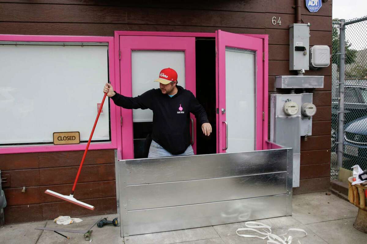 1月3日，粉红洋葱老板马修·科里奇爬过他的家人在他的教会区餐厅前建造和安装的金属防洪门。到2022年，防止洪水。