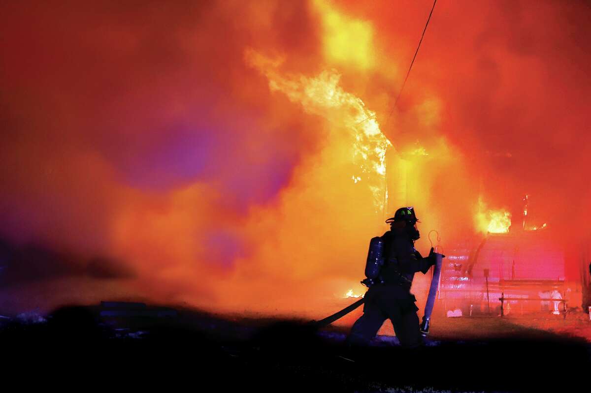 John Badman|The Telegraph A firefighter pulls a hose into place late Tuesday at a house on fire in the 1300 block of Deanna Avenue in Cottage Hills. A deputy reported the fire which had partially engulfed the house before firefighters were even called. 