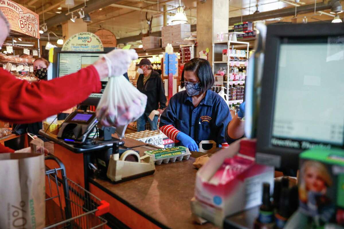 Noreen Dosayla (center) checks out customers at Canyon Market in San Francisco in 2020. Canyon Market founder Richard Tarlov said shoppers Tuesday "wiped out" supplies of protein and produce.