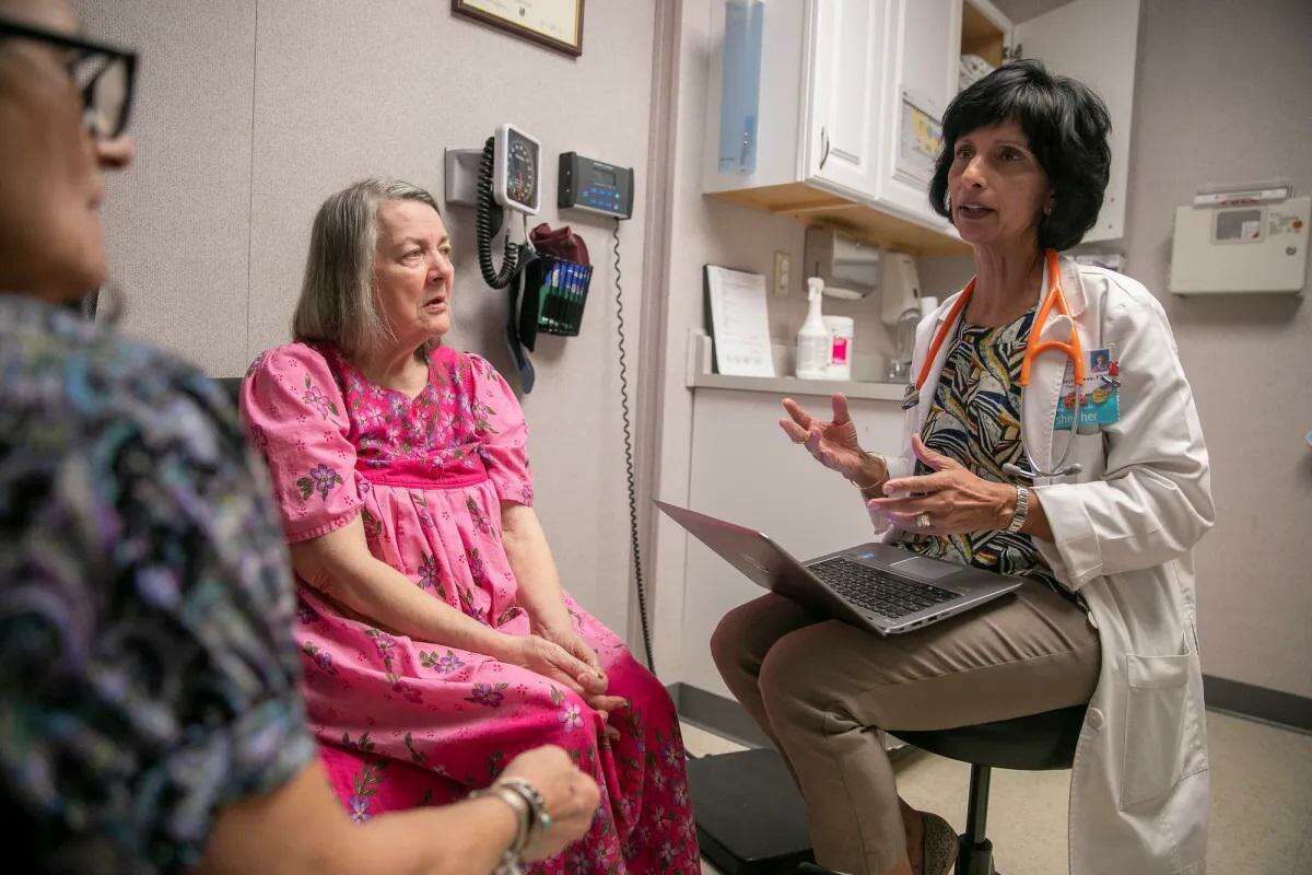 2020年，在俄罗斯河健康中心进行检查时，执业护士苏拉尼·海尔-坤(右)与病人玛丽·瓦莱萨诺(中)和她的护理人员乔治亚·马诺拉科斯-弗雷利(左)交谈。
