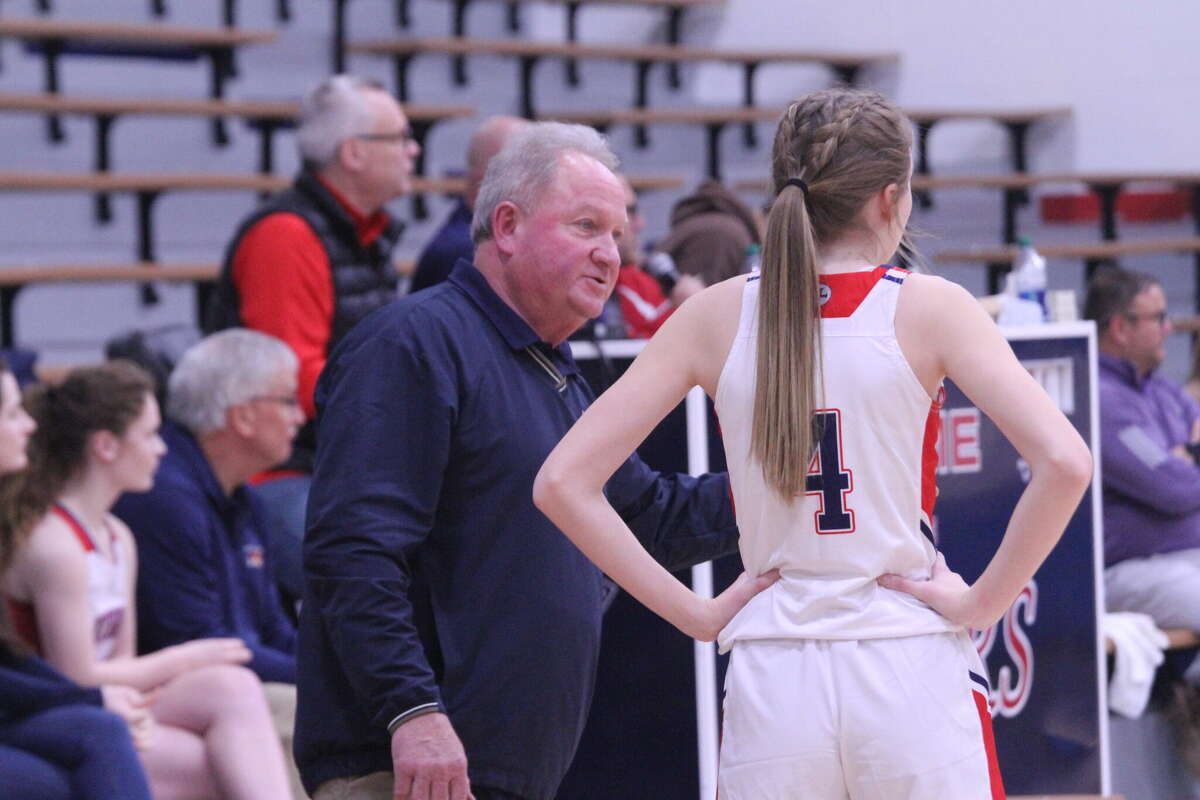 MCC head coach Todd Erickson (left) and Elizabeth Logan (right) converse while the Sabers shoot free throws on Jan. 4.