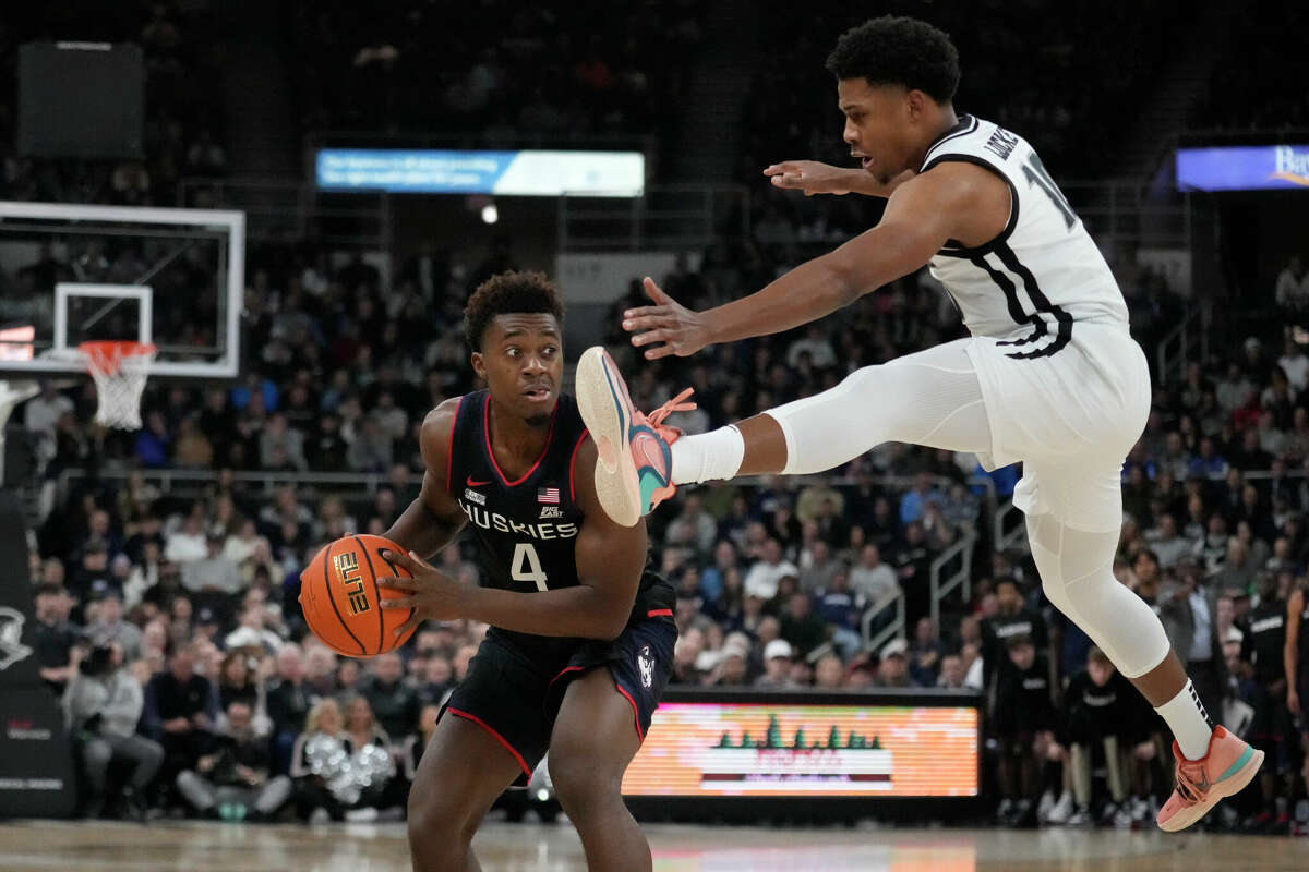 Providence guard Noah Locke, right, leaps while keeping the pressure on Connecticut guard Nahiem Alleyne (4) during the first half of an NCAA college basketball game, Wednesday, Jan. 4, 2023, in Providence, R.I. (AP Photo/Charles Krupa)