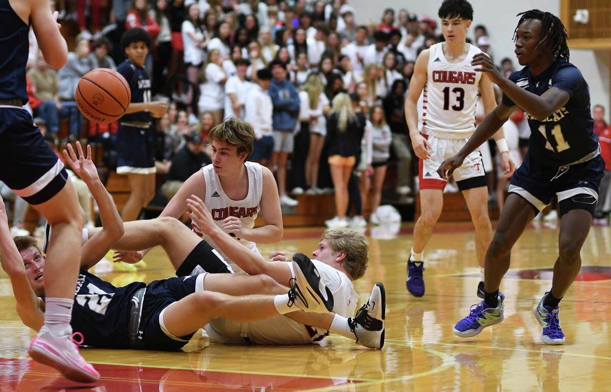 Tomball Memorial senior center Reed Odell, left, makes a pass from the floor against Tomball junior forward Aldan Waldron (right on the floor) during the second quarter of their District 15-6A matchup at Tomball High School on Wednesday, Jan. 4, 2023.