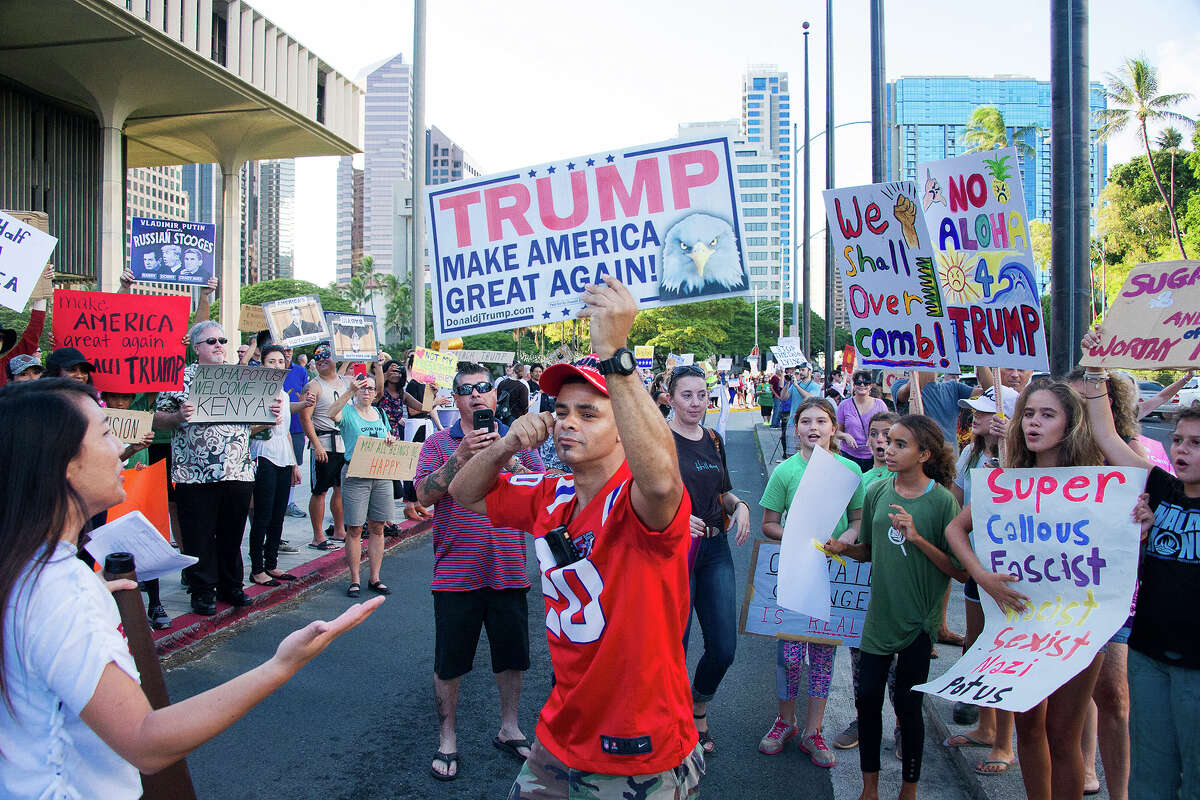 Edward Odquina, center, who holds a Trump Make America Great Again sign, confronts an anti-Trump crowd protesting at the capitol in Honolulu, Friday, Nov. 3, 2017.