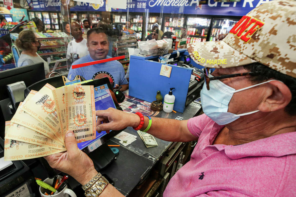 Ronald Marine, right, sells $200 worth of Mega Millions lottery to Paul Sandoval, as jackpot tops $1 billion at Bluebird Liquor on Friday, July 29, 2022 in Hawthorne, CA. The jackpot has once again climbed to nearly $1 billion in the Jan. 6, 2023 drawing.