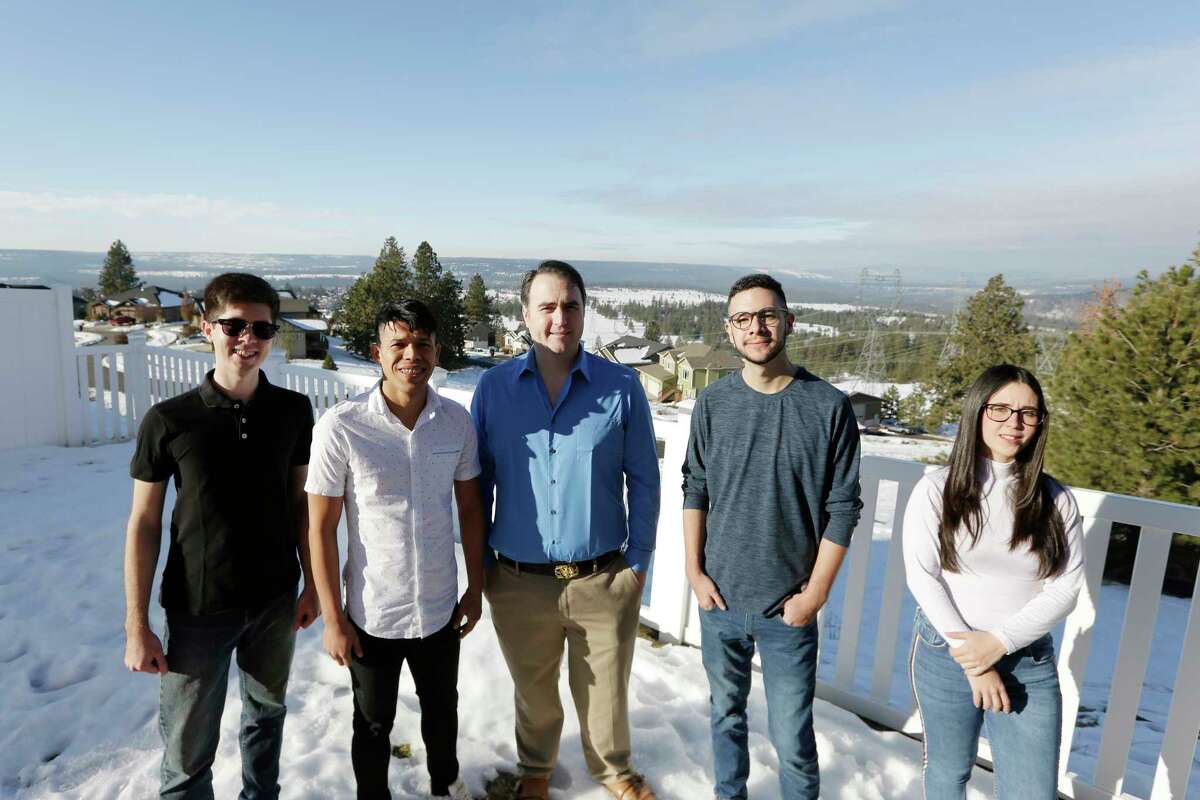 Dr. Kyle Varner, center, who sponsors and houses people through the Venezuelan humanitarian parole program, poses for a photograph at his house with program beneficiaries, from left, Cesar Baez, Jenderson Rondon, Henry Nadales and Maria Amare, Friday, Jan. 6, 2023, in Spokane, Wash.